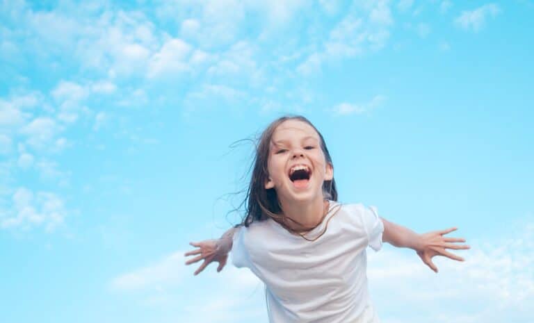 Child with wide smile and arms out behind her