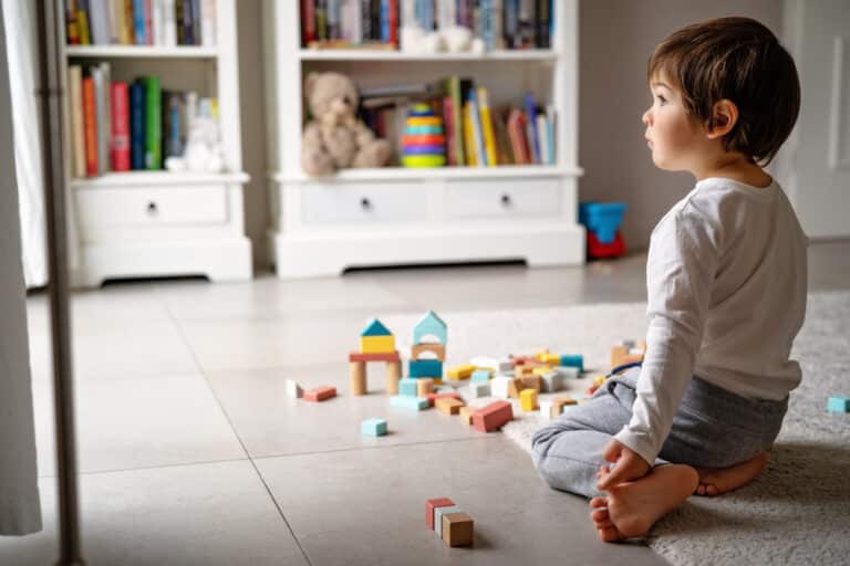 Little boy playing with toys on the floor alone