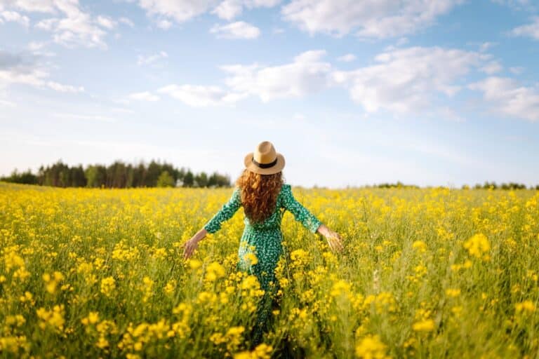 Woman walking in field of yellow flowers